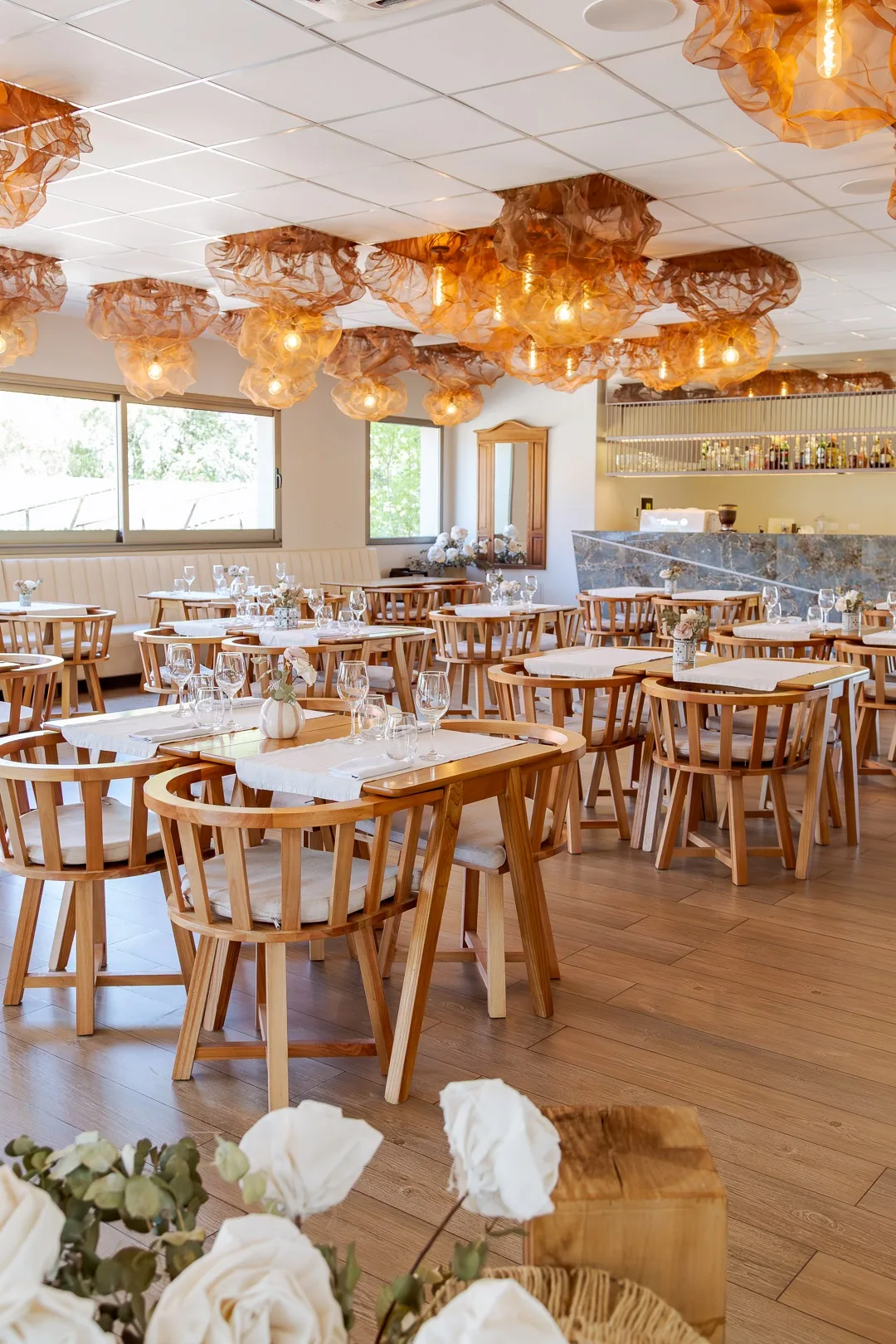 Salón del restaurante Buongiorno con mesas puestas, sillas de madera y lámparas de tela cobriza