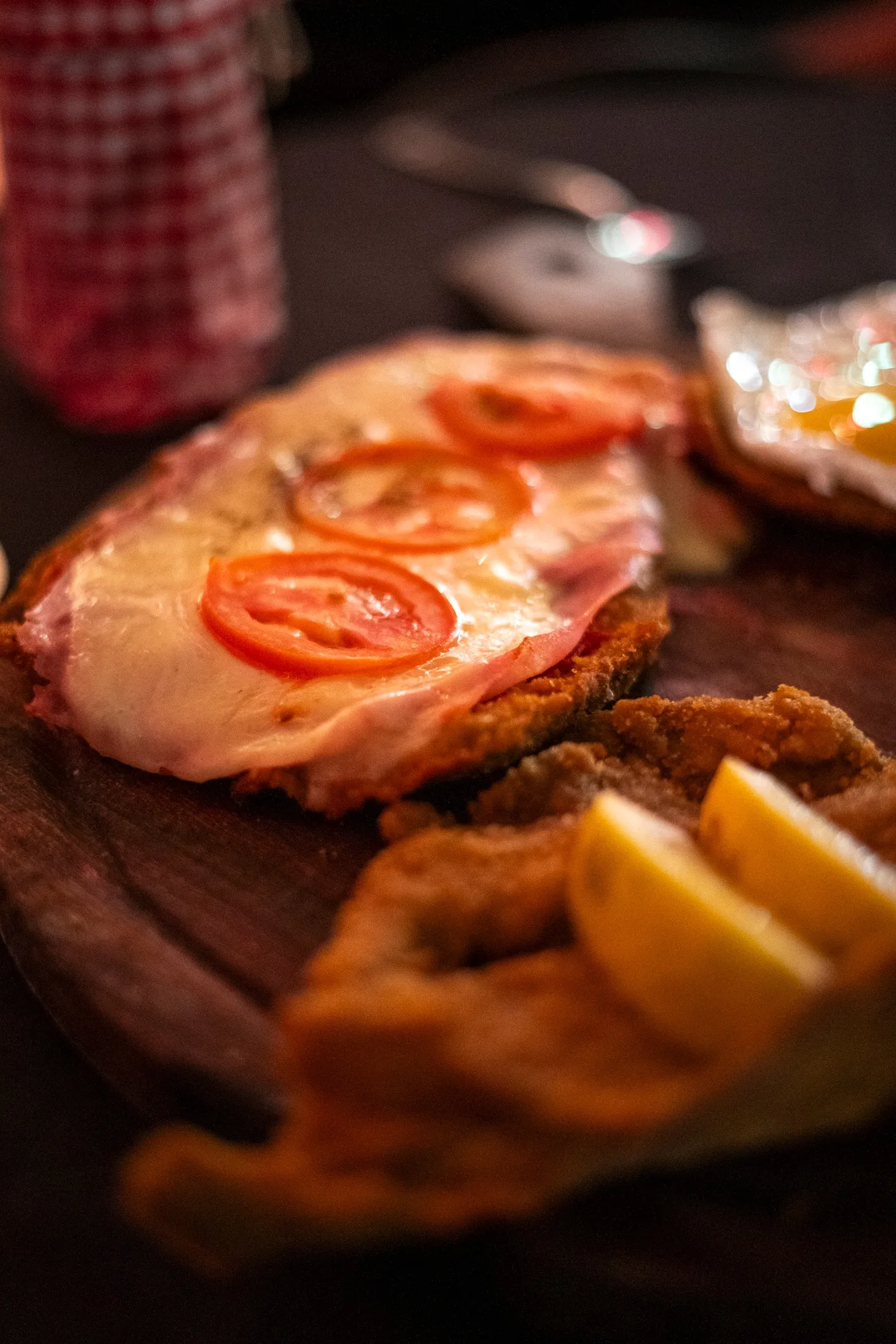 Milanesa a la napolitana con rodajas de tomate y limón sobre una tabla de madera