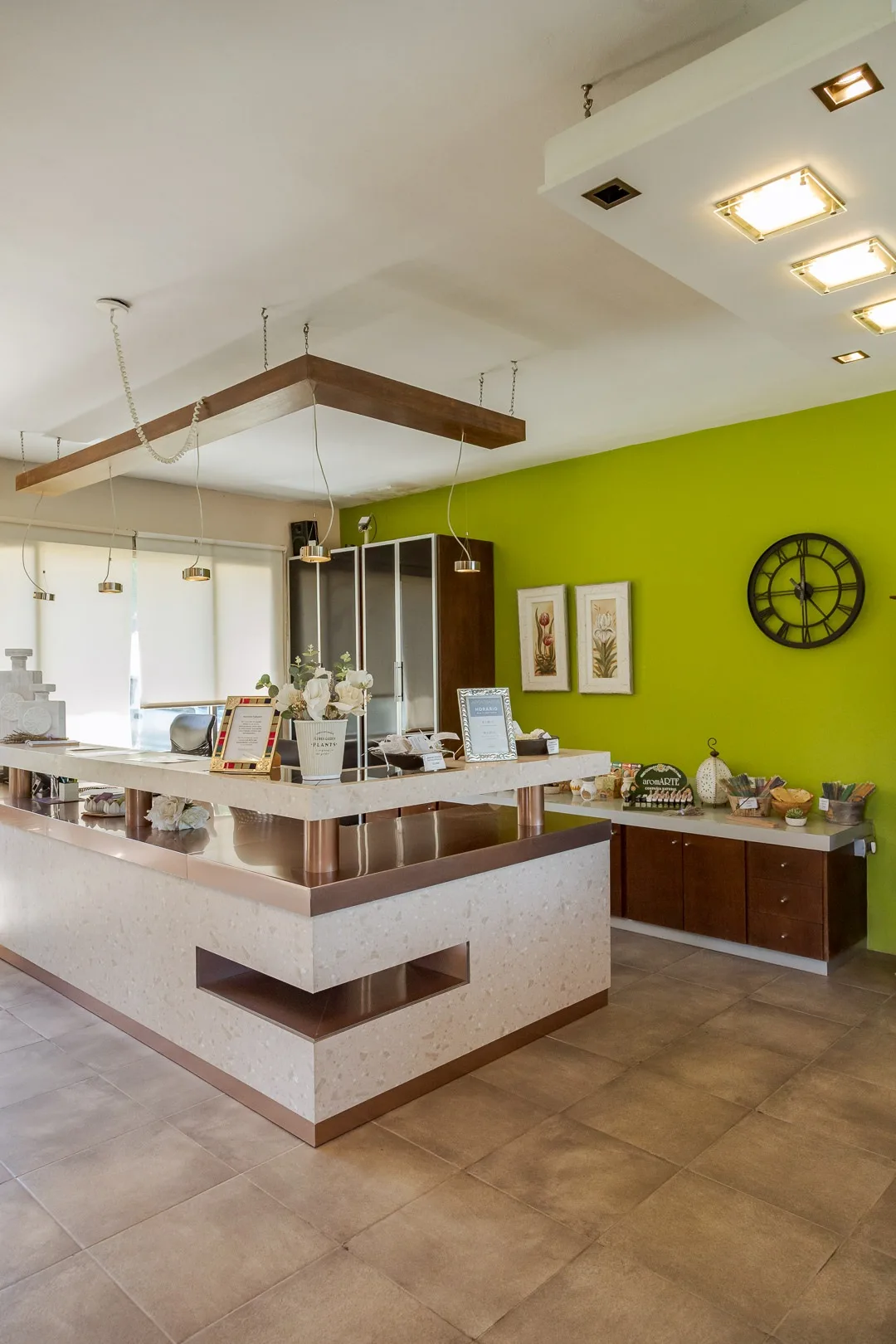 Recepción del spa con mostrador de piedra, pared verde lima y reloj